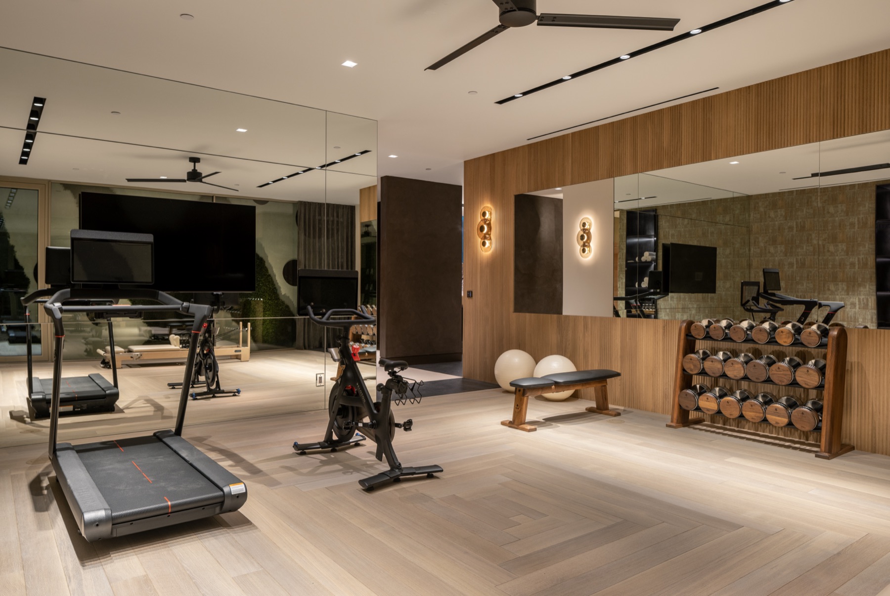 Lower-level gym at 3512 Ocean Boulevard with walnut dumbbells and cardio equipment