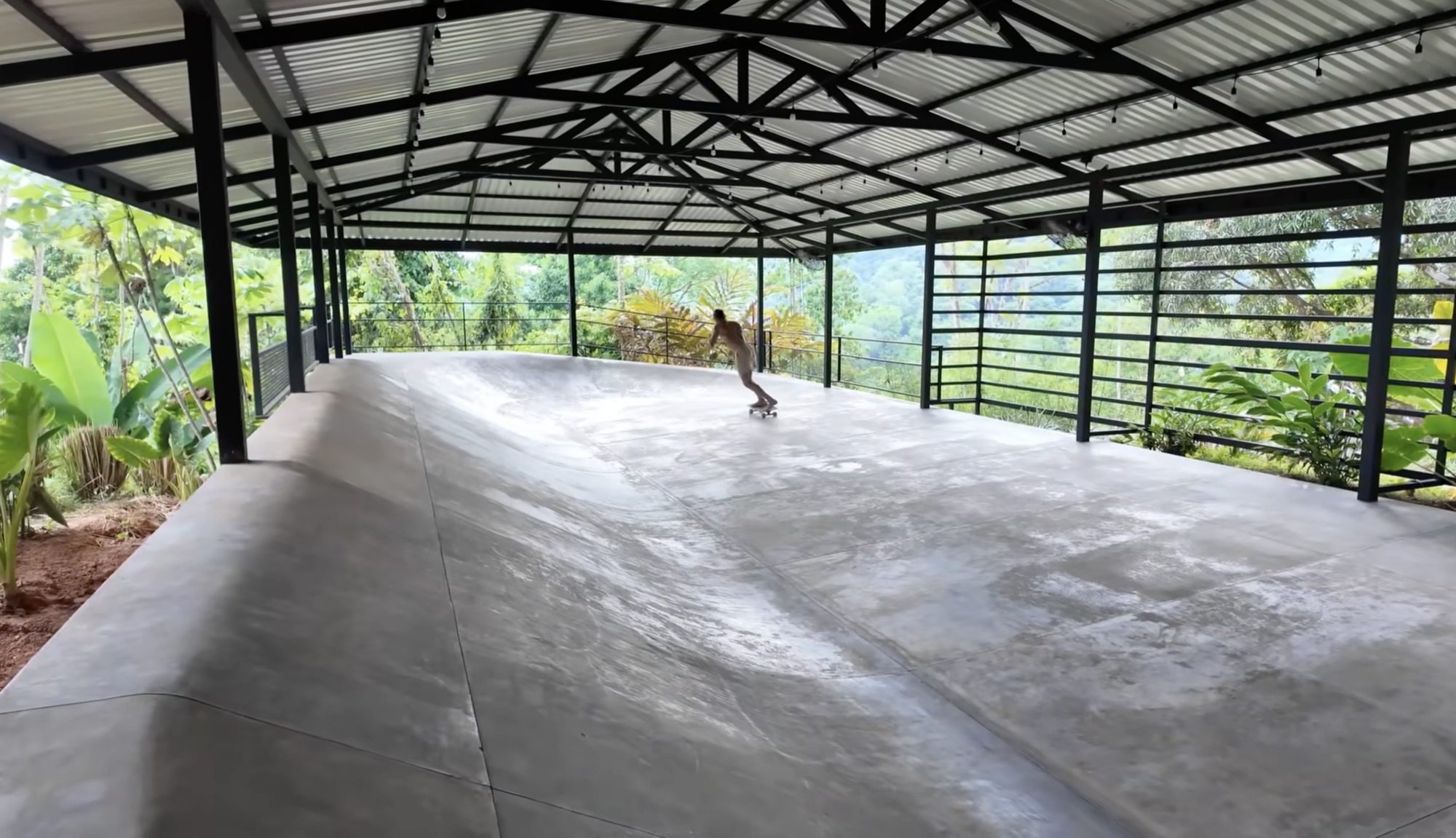 Covered half-pipe skate ramp with jungle ridge in the background