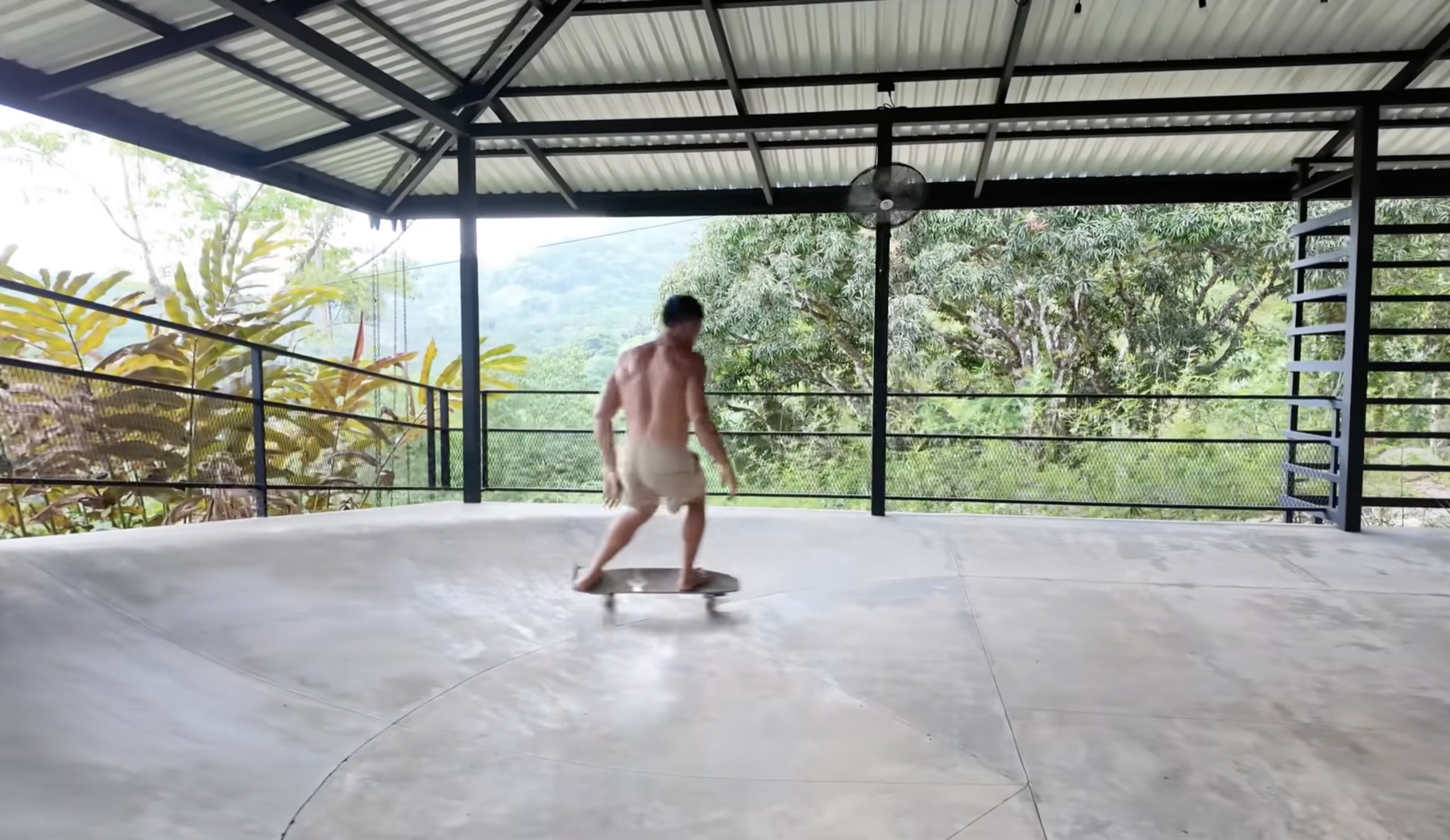 Paul on a balance board on the half-pipe's flat concrete pad, facing out over the jungle ridge