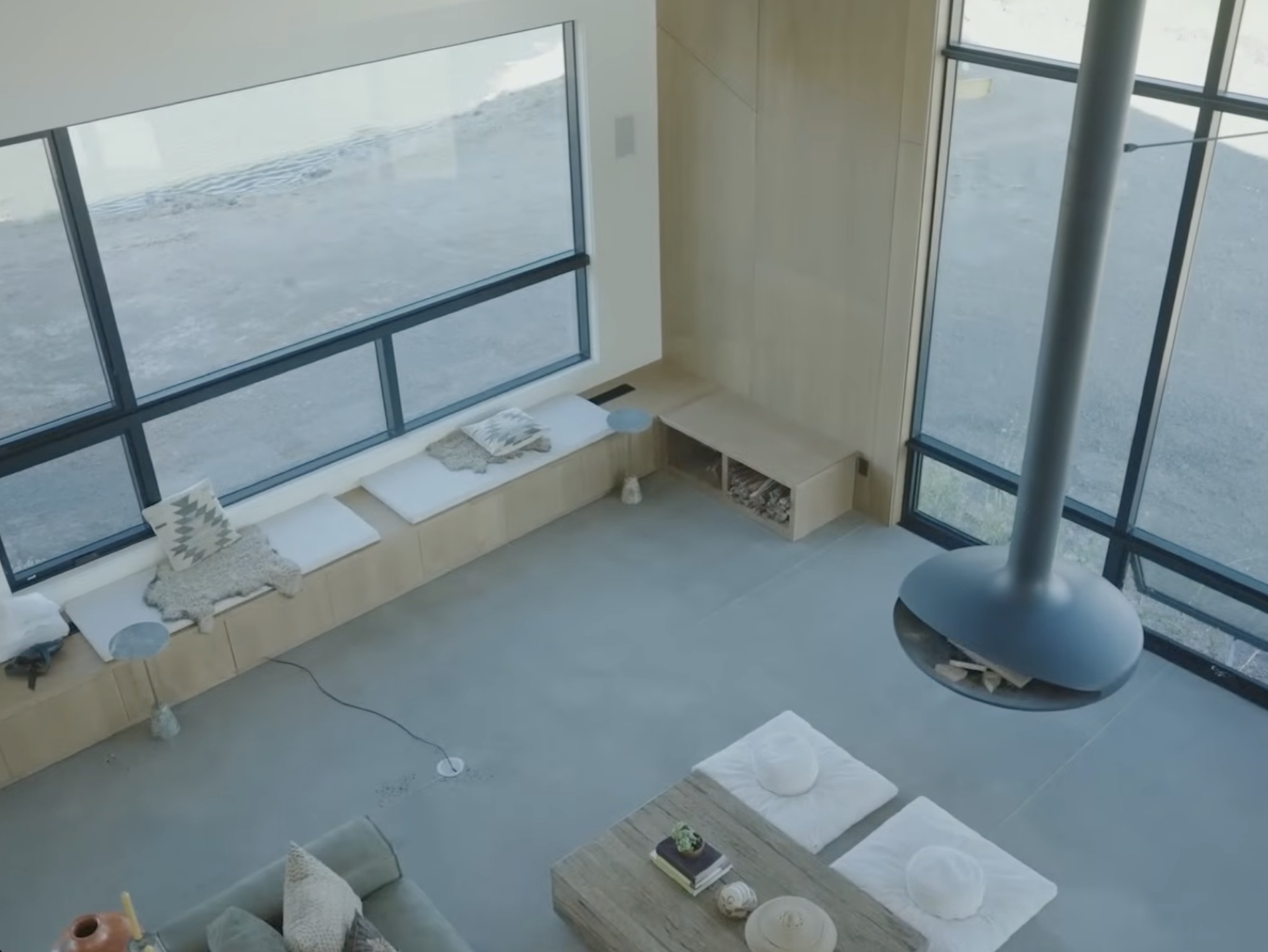 Living room with floor-to-ceiling windows, polished concrete floors, and suspended sculptural fireplace