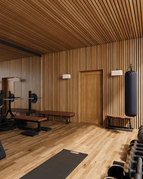 Weight bench with barbell and chains beside an oak door and hanging heavy bag in the slatted gym